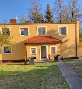 a yellow house with a red roof at Willa Rudno Nad Jeziorem in Rudno