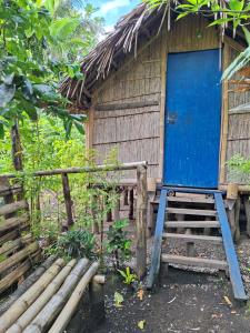a house with a blue door and steps in front at Ash and Ocean BUNGALOW in Loméméti