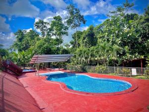 a small swimming pool with a red floor and a fence at Centro Turístico Las Palmitas in Muelle del Arenal