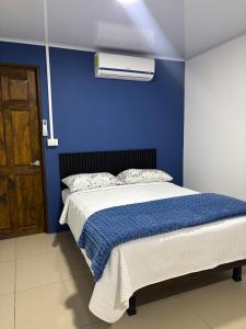 a blue bedroom with a bed with a blue wall at Centro Turístico Las Palmitas in Muelle del Arenal
