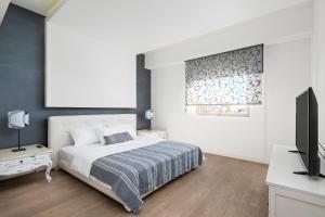 a white bedroom with a bed and a television at City Penthouse in Larnaca +10 photos