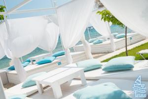 a row of white beds with blue pillows on the beach at Tarsanas Studios in Limenas