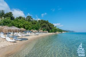 a beach with chairs and umbrellas and the water at Tarsanas Studios in Limenas