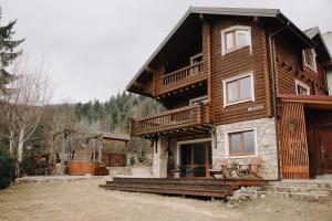 a large log house with a porch and a balcony at Vidal in Tatariv