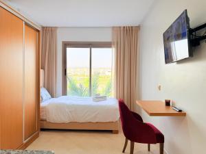 a bedroom with a bed and a desk and a window at Stay with US in Agadir
