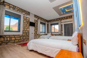 a bedroom with two beds in a room with windows at Relais Des Nomades in Tinerhir