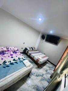 a small room with two beds and a tv at Hospedaje De Joce in Nazca