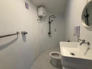 a white bathroom with a toilet and a sink at Highland Bali in Baturaja