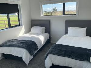 two beds in a room with two windows at Blacksmith's Rest in New Plymouth