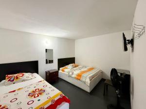 a bedroom with two beds and a chair in it at Hospedaje DJ in Buga +7 photos