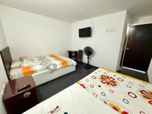 a small room with two beds and a fan at Hospedaje DJ in Buga