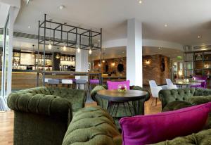 a lobby with green couches and a table and a bar at Hilton Garden Inn Birmingham Brindley Place in Birmingham