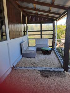 a screened in porch with two chairs and a table at Hospedaje La Guaca in Bagaces