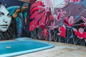 a bath tub in front of a wall with a mural at Pousada Zayon Jeri in Jericoacoara +8 photos