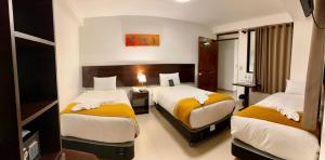 a hotel room with two beds with yellow and white sheets at PisonayMapiHotelBoutique in Machu Picchu
