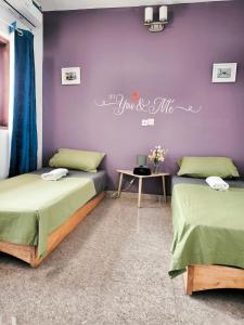 two beds in a room with a purple wall at O'soho GarDens BingerVille in Bingerville +27 photos