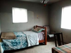a bedroom with a bed and a chair and two windows at Comfy Room 2 in Overland Park