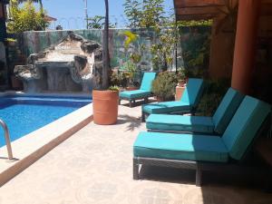 a pool with two blue chairs and a swimming pool at "Le Petit Oasis" Pool, AC and Beach 1 minute away in La Peñita de Jaltemba