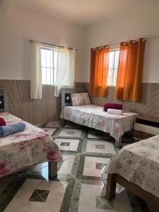 a room with two beds and two windows at Pousada Vale do Catimbau in Buíque