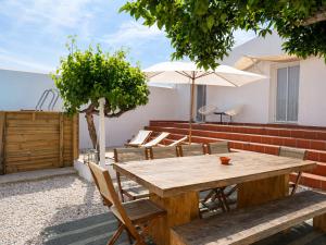 a wooden table with chairs and an umbrella on a patio at Casa das Lages in Pedrógão