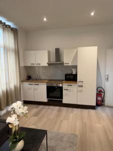 a large kitchen with white cabinets and a table at Stylish 1BR Apartment Close to City Center Liège in Liège