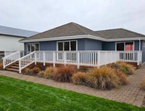 a house with a white deck and landscaping at Tauranga Backpackers - Private Guest Rooms by the Water! in Tauranga