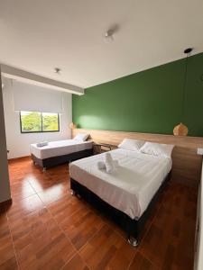 a bedroom with two beds and a green wall at Amazon Garden Suites - Recojo del aeropuerto incluido in Pucallpa