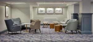 a waiting room with chairs and tables and paintings at Hilton Cobham in Cobham