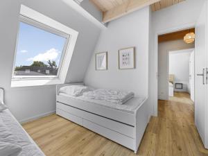 a white bedroom with a bed and a window at Schulzenhufe an der Ostsee in Beckerwitz