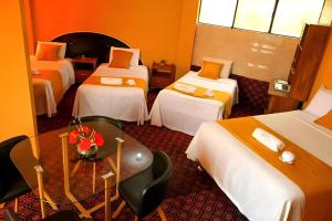 a hotel room with four beds and a table with flowers at Hotel San Lázaro Arequipa - Cochera - Hotel en Arequipa in Arequipa +2 photos