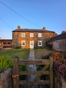 an old brick house with a fence in front of it at Postmasters House in Helston