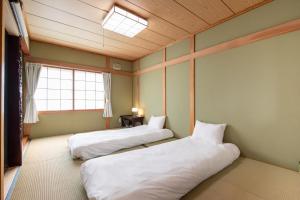 two beds in a room with a window at House Of Joy Furano -15 mins to ski resort- in Furano