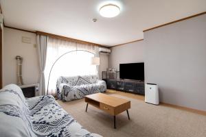 a living room with a couch and a tv at House Of Joy Furano -15 mins to ski resort- in Furano