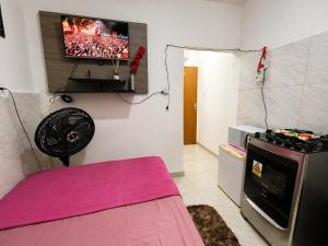 a room with a fan and a tv on the wall at Kitnet Dream House 2 in Bayeux