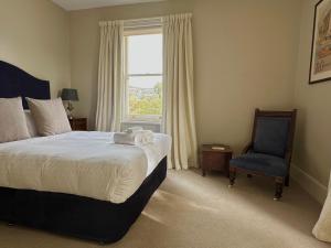 a bedroom with a bed and a chair and a window at Old Bishop's Quarters in Hobart