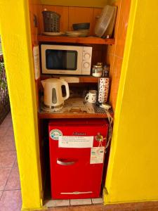 a small kitchen with a microwave and a red refrigerator at Hostal El Punto in La Serena