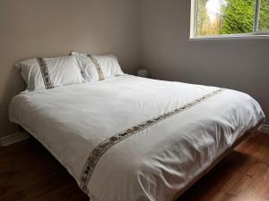 a bed with white sheets and a window in a room at Bloom House 樱花民宿 in White Rock