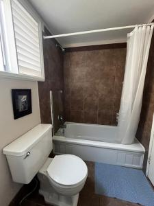 a bathroom with a toilet and a tub and a sink at Bloom House 樱花民宿 in White Rock