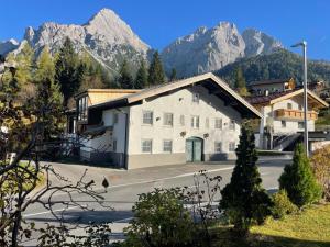 a large white building with mountains in the background at Biber Art Apartment 2 Small in Biberwier