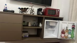 a microwave sitting on top of a shelf with an open refrigerator at HABITACION MODERNA CON PARQUEO y WIFI in Ambato +15 photos