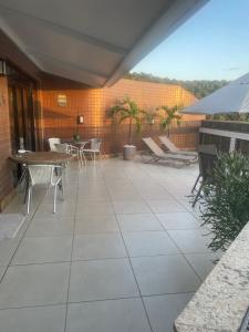 a patio with tables and chairs and a table at Paraíso à vista Cobertura Linear Canto Nobre in Guarapari