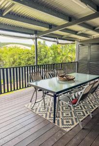 a glass table and chairs on a deck at Panacea Rising in Yeppoon