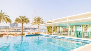 a swimming pool in front of a building with palm trees at DoubleTree by Hilton Dubai Jumeirah Beach in Dubai