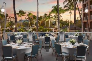 a restaurant with white tables and chairs and palm trees at DoubleTree by Hilton Grand Key Resort in Key West