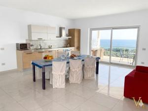 a kitchen with a blue table with chairs and a kitchen with a window at VILLA ARCANGELO Le in Mandatoriccio Marina