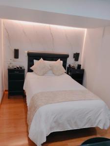 a bedroom with a large white bed with two night stands at Hotel Veler in Medellín