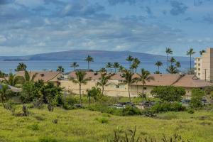 a building with palm trees in front of the water at Kihei Alii Kai Ocean View Condo Pool, Hot Tub, Sauna, AC, Sleeps 4 in Kihei