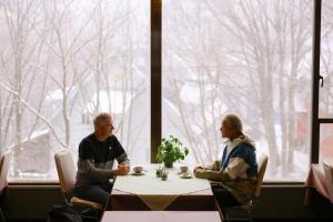 two men sitting at a table in front of a window at Hotel Silk Inn Madarao in Iiyama