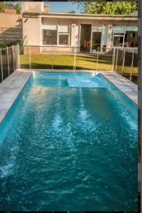 a swimming pool with blue water in front of a house at QUINTA CERRO LARGO Olavarria in Olavarría