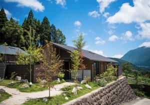 a house in the mountains with a stone wall at エンゼルグランヴィラ由布院 in Yufu